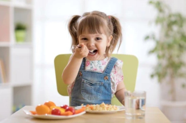 Young child enjoying a healthy meal with fresh fruits and nutritious food at the dining table.