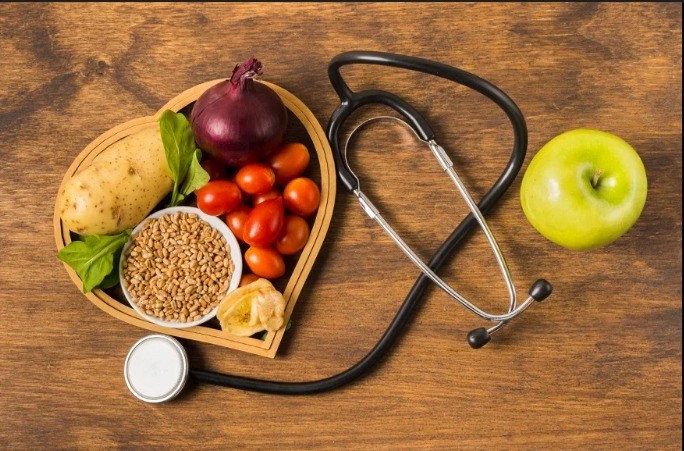 Healthy nutrition and heart care concept with fresh vegetables, whole grains, fruits, and medical stethoscope.