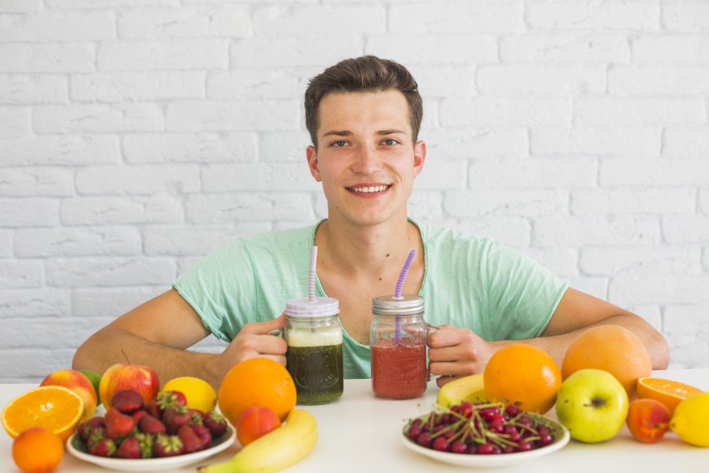 Young man enjoying fresh fruit juices and healthy fruits as part of a balanced nutrition lifestyle.