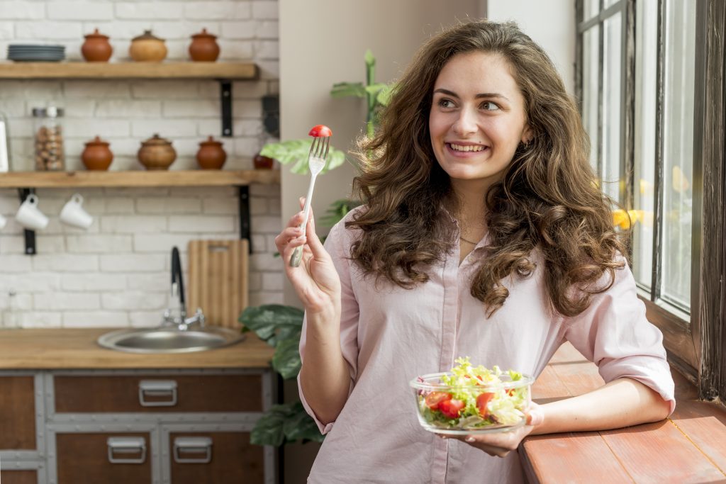 Woman enjoying a fresh salad and healthy vegetables as part of a balanced nutrition lifestyle.