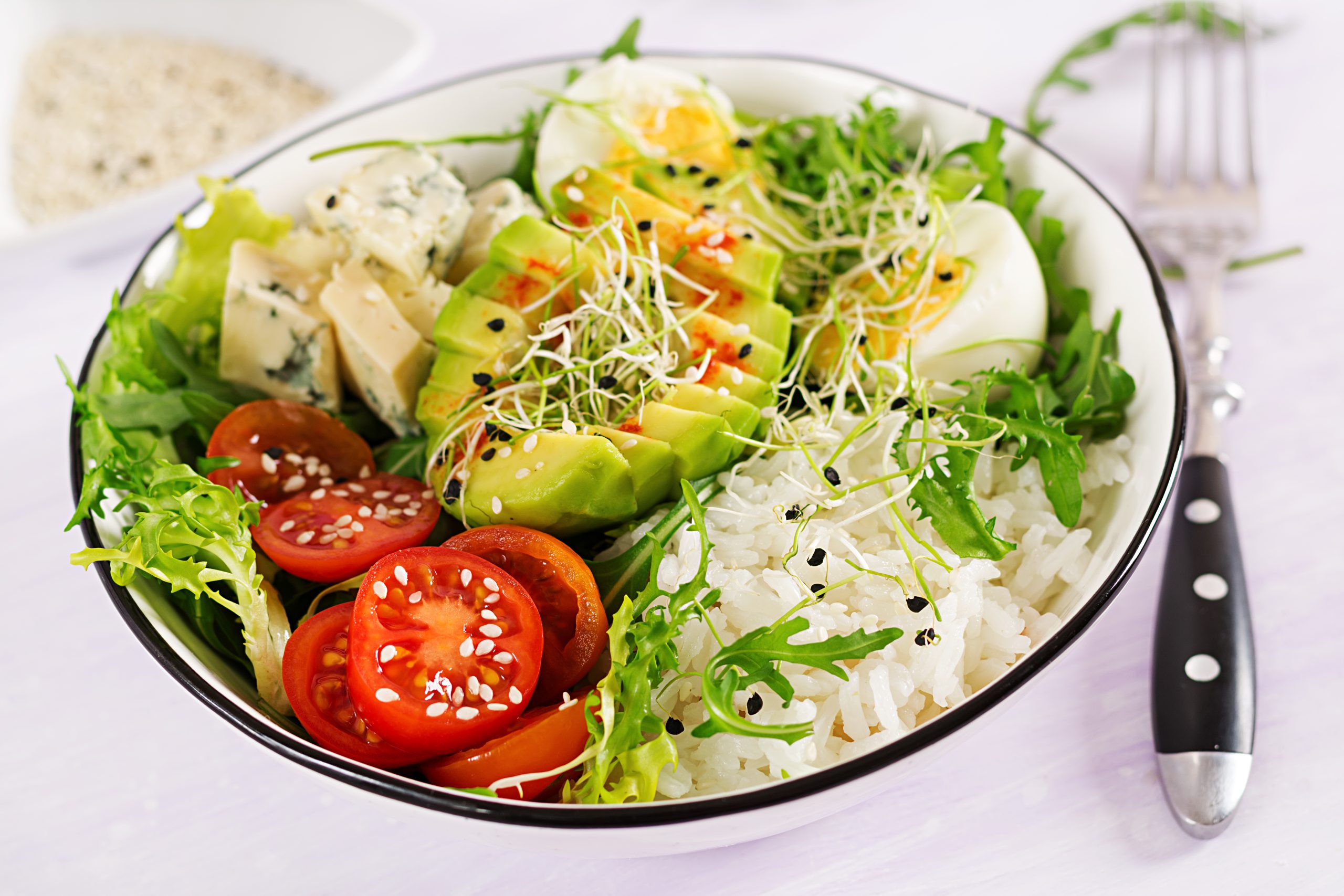 Healthy meal bowl with rice, avocado and vegetables.