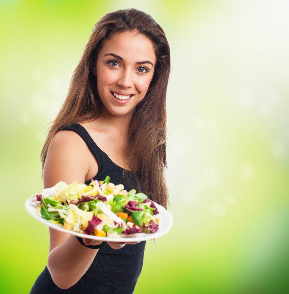 Woman holding a fresh salad bowl while promoting healthy eating and balanced nutrition lifestyle.